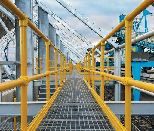 Industrial walkway with yellow FRP handrails and grating platform installed by Machs