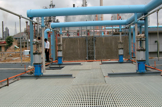 Industrial platform with FRP grating flooring supporting blue pipelines and equipment in a chemical plant.