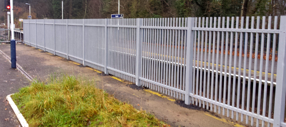 Grey GRP palisade fencing installed along a railway platform, providing non-conductive and corrosion-resistant perimeter security.