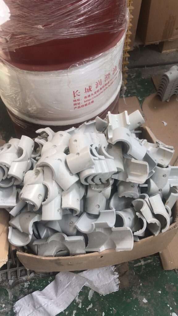 Bulk FRP handrail clamp rings packed in cartons, placed beside resin barrels in the workshop.