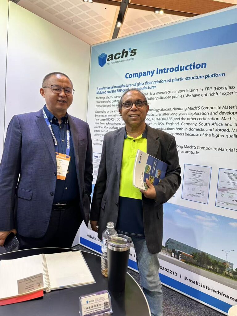 Machs representative with international visitor at AIMEX 2024 booth, introducing FRP solutions and company background.